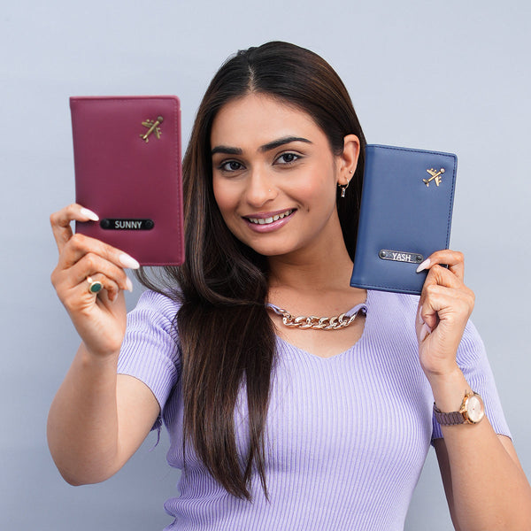 Woman holding two personalized vegan leather passport covers—one Prussian blue and one burgundy—ideal travel accessories for couples.